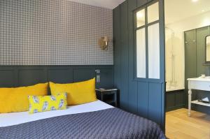 レ・ゼイジー・ド・タヤックにあるLes Glycines - Hôtel & Spa - Teritoriaのベッドルーム1室(黄色い枕のベッド1台付)、バスルーム1室が備わります。