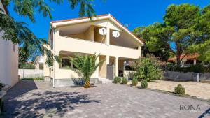 a white house with a palm tree in front of it at Rona apartments Goran in Šimuni