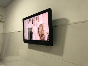 un televisor en una pared con una mujer en él en Kitnets da vana, en Morro de São Paulo