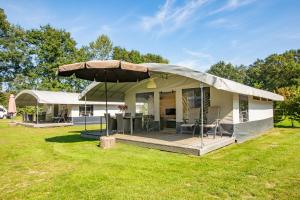 ein Haus mit einer Terrasse und einem Sonnenschirm in der Unterkunft Vakantiepark de Witte Berg in Ootmarsum