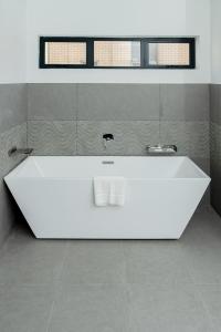 a white bathtub in a bathroom with two windows at LOCH LOGAN HOTEL in Bloemfontein