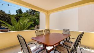 a wooden table and chairs on a balcony at Rona apartments Goran in Šimuni
