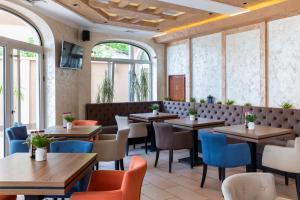 um restaurante com mesas e cadeiras de madeira e janelas em Garni Hotel Royal Crown em Subotica
