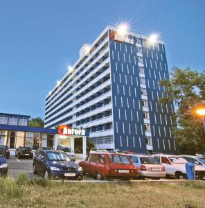 a tall building with cars parked in a parking lot at Hotel Aurora in Mamaia