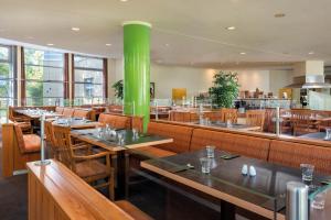 a restaurant with wooden tables and a green pillar at Seminaris SeeHotel Potsdam in Potsdam