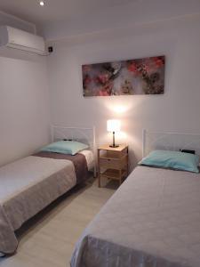 two beds in a room with a painting on the wall at F & P apartment in Kardamaina