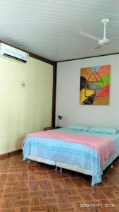 1 dormitorio con 1 cama y una pintura en la pared en Casa Mota Acolhedora x Bem Localizada x Um Minuto da Praia en Santarém