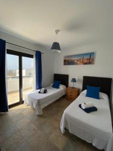 Duas camas num quarto com uma janela grande em Villas Thiago em Tinajo