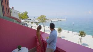 un uomo e una donna in piedi su un balcone che guardano l'acqua di Veya Hotel by Aminess a Njivice