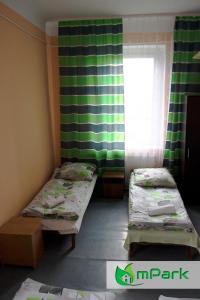 2 łóżka w małym pokoju z oknem w obiekcie Hostel Noclegi Chorzow w mieście Chorzów