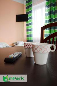 a table with two cups and a remote control on it at Hostel Noclegi Chorzow in Chorzów