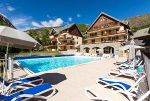 une piscine avec des chaises longues et un hôtel dans l'établissement Résidence Odalys Les Sybelles, à Saint-Sorlin-dʼArves