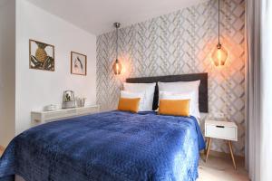 sypialnia z niebieskim łóżkiem z pomarańczowymi poduszkami w obiekcie City Center Apartament IMPERO z Parkingiem w Poznaniu