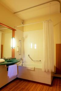 uma casa de banho com uma banheira, um chuveiro e um lavatório. em ibis Grenoble Université em Gières