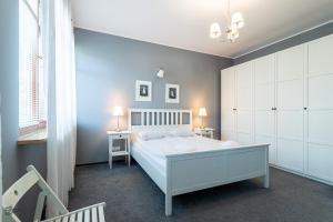 a bedroom with a white bed and a blue wall at Victus Apartamenty, Apartament Lighthouse in Gdańsk