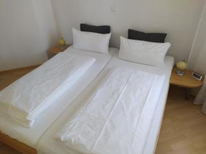 1 cama blanca grande con sábanas y almohadas blancas en Thermen-Residenz, en Bad Füssing