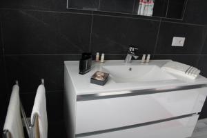 a white sink in a bathroom with black tiles at Agriturismo Nona Emma in Piano Porlezza