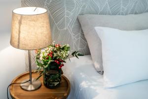 un tavolo con una lampada e un vaso di fiori su un letto di Hôtel & Séminaire Le Patio Occitan - Toulouse Ouest - La Ramée a Cugnaux