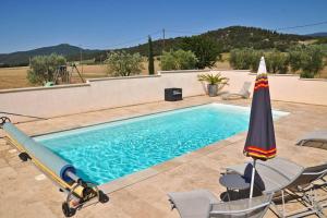 a swimming pool with an umbrella and chairs at Le gîte du Jas Vieux in Montfort