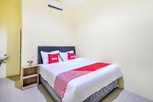 ein Schlafzimmer mit einem großen Bett mit roten Kissen in der Unterkunft Super OYO 2509 Hotel Tebel 19 in Gedangan