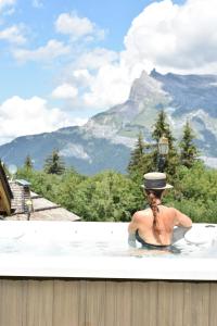a man in a bath tub with a hat in the mountains at Le Hameau Du Renard Blanc in Saint-Gervais-les-Bains