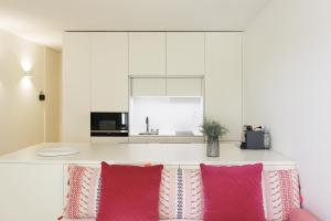 uma cozinha com armários brancos e almofadas cor-de-rosa em HM - Historical Studio Taipas 3E no Porto