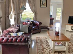 a living room with two leather couches and a table at TÍ Mhaggie Holiday Cottage by Trident Holiday Homes in Gowla