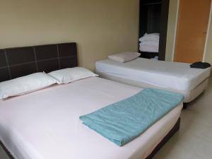 two twin beds in a room with at Kinora Homestay in Perai