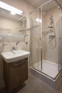 W łazience znajduje się umywalka i prysznic ze szklanymi drzwiami. w obiekcie Rewita Korab w mieście Sopot