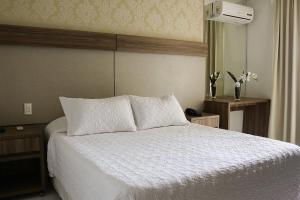 Schlafzimmer mit einem weißen Bett und einem Spiegel in der Unterkunft Aram Ponta Negra in Natal