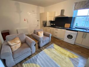 a living room with two chairs and a kitchen at Stylish 2nd Floor Georgian 1 Bedroom Apartment in Dumfries