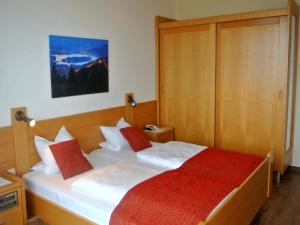 um quarto com uma cama com lençóis brancos e almofadas vermelhas em Hotel Baumgartnerhof em Altfinkenstein