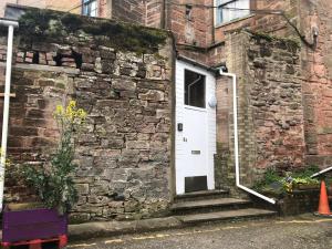 a brick building with a white door and stairs at Stylish 2nd Floor Georgian 1 Bedroom Apartment in Dumfries