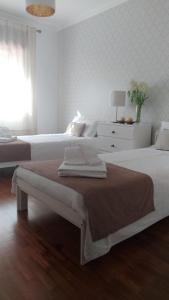 una camera da letto bianca con due letti e una finestra di Casa O'lado a Golegã