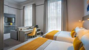 a hotel room with two beds and a desk at Maldron Hotel Parnell Square Dublin City in Dublin +12 photos