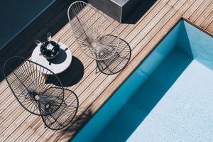 2 sedie e un tavolo su una terrazza accanto alla piscina di More Meni Residence & Suites a Tigaki