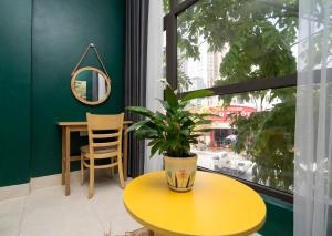 a yellow table with a potted plant on it in front of a window at VietHouse Homestay Ha Long in Ha Long