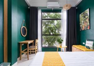 1 dormitorio con cama, ventana y escritorio en VietHouse Homestay Ha Long, en Ha Long