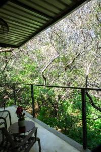 a balcony with a table and chairs and trees at Nehema Manor in Hartbeespoort