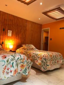 2 camas en un dormitorio con paredes revestidas de madera en Hostal Posada Angelmo, en Puerto Montt