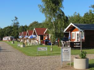 een rij cottages met borden voor hen bij Holme Å Camping & Cottages in Hovborg
