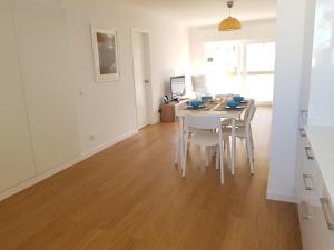 een witte eetkamer met een witte tafel en stoelen bij Sol Da Caparica in Costa da Caparica