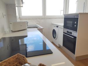 uma cozinha com um lavatório e uma máquina de lavar roupa em Sol Da Caparica em Costa da Caparica