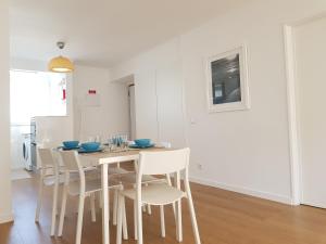 een witte eetkamer met een tafel en stoelen bij Sol Da Caparica in Costa da Caparica