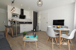 a living room with a table and chairs and a kitchen at Le First by EasyEscale in Romilly-sur-Seine