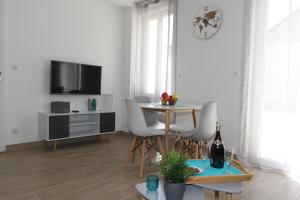 a living room with a table and a tv at Le First by EasyEscale in Romilly-sur-Seine