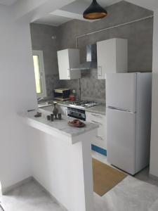 Il comprend une cuisine équipée d'appareils électroménagers blancs et d'un réfrigérateur blanc. dans l'établissement Apparts zayatine, à Tunis