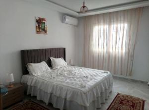 a bedroom with a bed with white sheets and a window at Apparts zayatine in Tunis