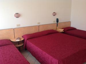 a room with two red beds and a table at Hotel Casali in Cervia