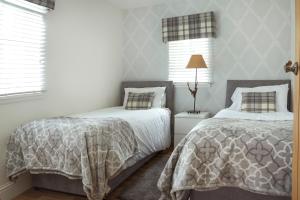 a bedroom with two beds and a lamp at The Lodge House Callander in Callander